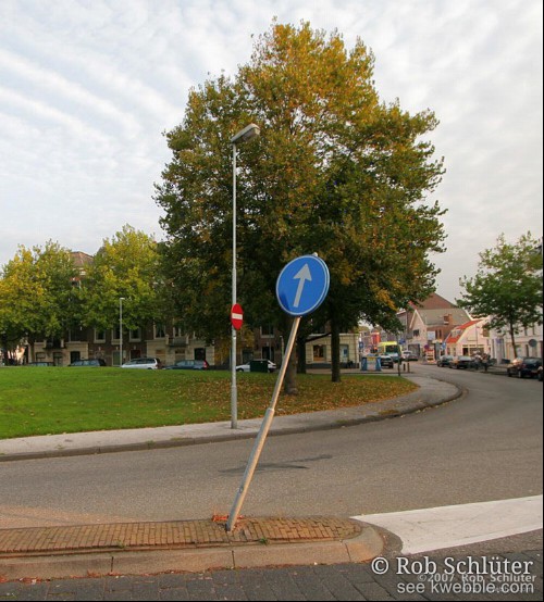 Op een verkeersdrempel wijst een bord voor eenrichtingsverkeer schuin omhoog.