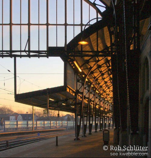 De opkomende zon beschijnt het plafond boven een perron van onderen.