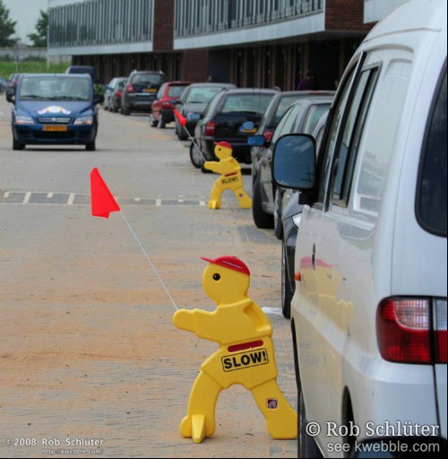 Op de weg in een nieuwe woonwijk staan 2 gele plastic poppetjes met het opschrift \